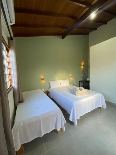 a bedroom with two beds with white sheets at Pousada Portal do Cerrado in Pirenópolis