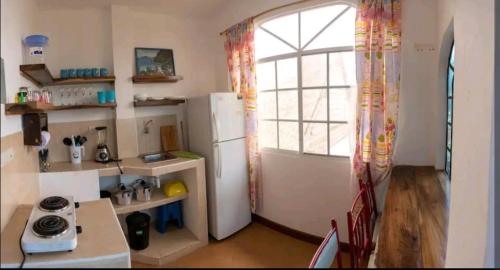 a kitchen with a white refrigerator and a window at Casa Mañana in Puerto López