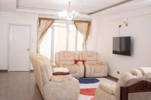 sala de estar con 2 sillas y TV en 4bedroom Navilla westlands Nairobi, en Nairobi