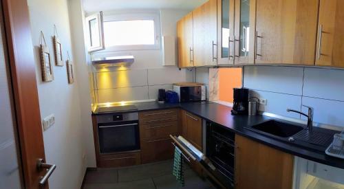 cocina con armarios de madera y encimera negra en 80 qm Apartment Alessia Nürnberg, en Núremberg