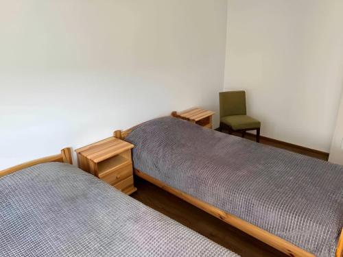 two beds in a room with a green chair at Augustòw Centre 1-Bedroom Comfort and Leisure. in Augustów