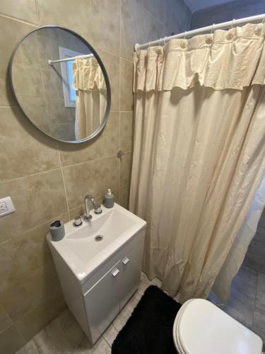 een badkamer met een wastafel, een spiegel en een toilet bij BOSQUE LIBERTAD Casa PB in Mar Azul
