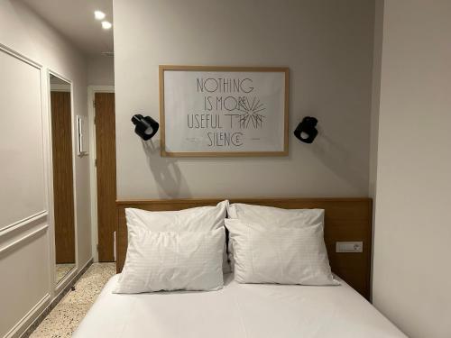 a bed with two pillows and a picture on the wall at Belle Athenes - Luxury Rooms at Monastiraki Railway Station in Athens