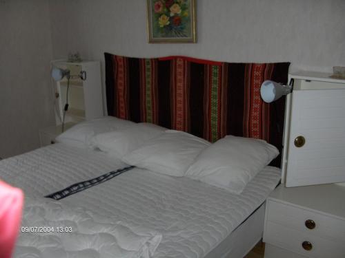 Una cama con sábanas blancas y almohadas en un dormitorio. en Holkestorp, en Onslunda