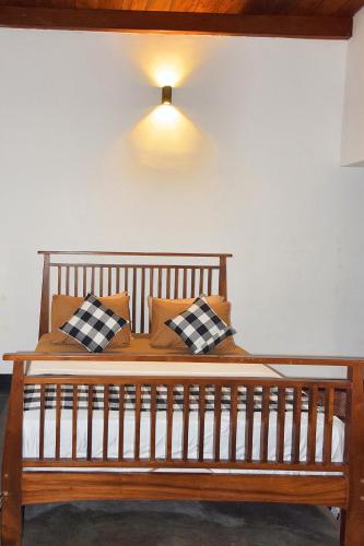 a wooden bed with pillows and a light on the wall at Villa RISITHENMI in Ahangama