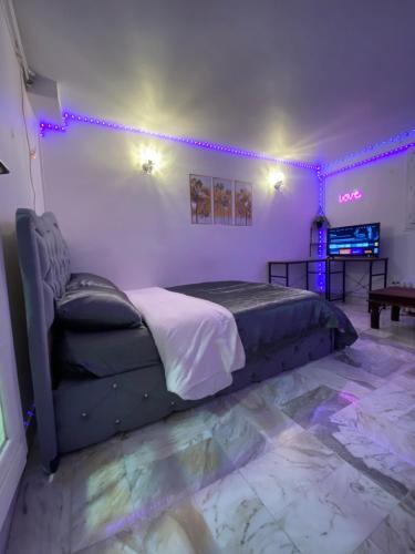 een slaapkamer met een bed in een kamer met paarse verlichting bij Nice Studio Livry in Livry-Gargan