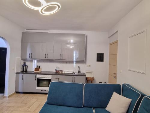 a living room with a blue couch and a kitchen at Lea Apartament in Sarandë