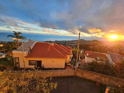 een uitzicht op een huis met de zonsondergang op de achtergrond bij Casa de Feria do Livramento in Funchal