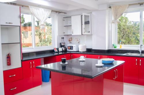 czerwona kuchnia z czarnymi blatami i czerwonymi szafkami w obiekcie 4bedroom westlands raphta Nairobi w mieście Nairobi