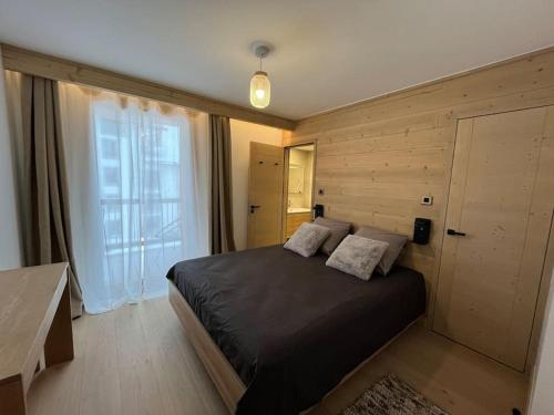 ein Schlafzimmer mit einem schwarzen Bett und einem großen Fenster in der Unterkunft La Terrasse de l Alpe d Huez in L'Alpe-d'Huez
