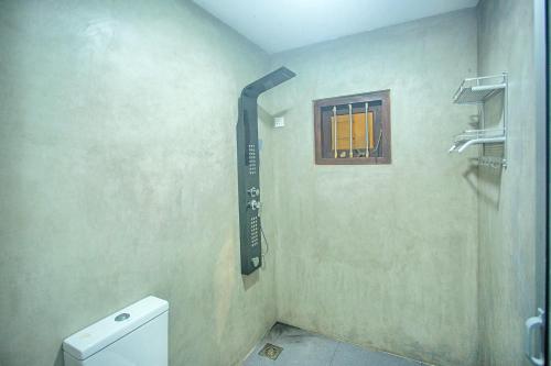 a bathroom with a shower and a toilet and a window at Villa RISITHENMI in Ahangama