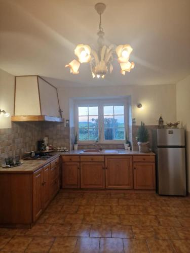 Il comprend une cuisine avec des placards en bois, un réfrigérateur et une fenêtre. dans l'établissement Belle maison a Brizay, à Brizay