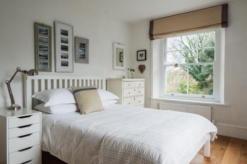 1 dormitorio con cama blanca y ventana en Devon Farmhouse en Kingsbridge