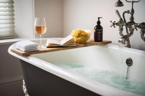 a bath tub with a book and a glass of wine at Devon Farmhouse in Kingsbridge