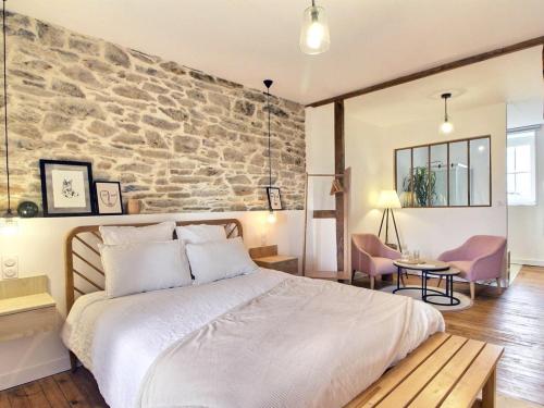 1 dormitorio con 1 cama grande y pared de piedra en Les Chambres D'Hespéris en Pleyben