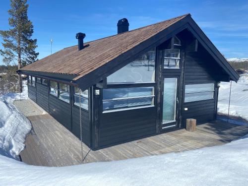 a building with a wooden deck in the snow at Hito - cabin between Flå and Eggedal in Flå