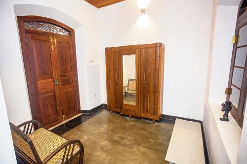 a hallway with a wooden door and chairs and a table at Villa RISITHENMI in Ahangama
