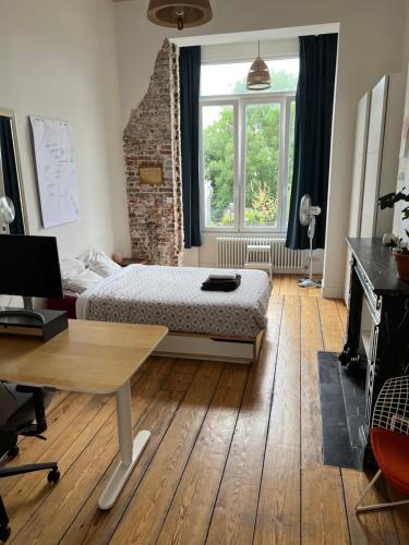 a bedroom with a bed and a desk and a window at Arti Appart Louise/Flagey/Centre in Brussels