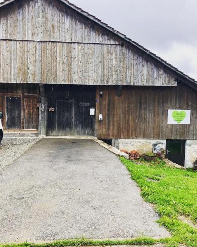 a large wooden barn with a parking lot in front at LaTerestone in Les Bayards