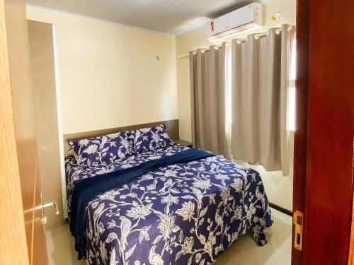 a bedroom with a blue and white bed and a window at Condomínio Lençóis Ville Residence in Barreirinhas