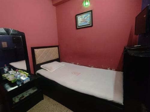 a small bedroom with a bed with a red wall at Hotel Hoque Tower International in Chittagong