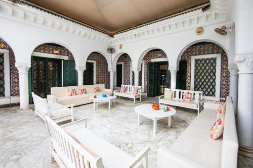 un patio al aire libre con mesas y muebles blancos en Arabesque House, en La Marsa