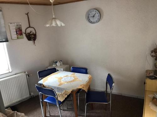 una mesa y sillas en una habitación con un reloj en la pared en Ferienwohnung, en Münchenbernsdorf