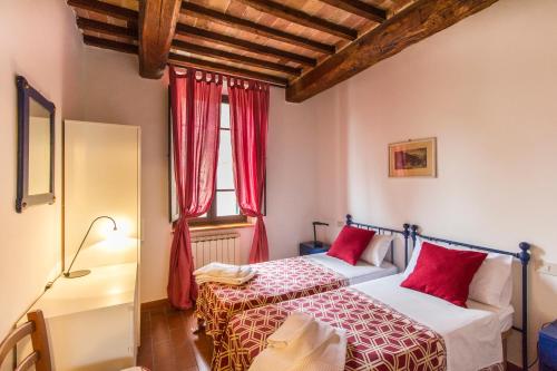 two beds in a room with red curtains at Appartamenti Villa e Fattoria di Radi Tuscany in Monteroni dʼArbia