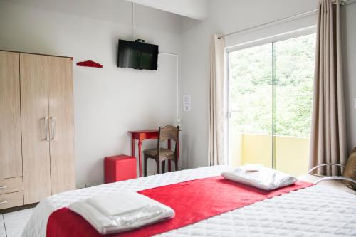 Hotel Grezelle في Santa Bárbara: غرفة نوم مع سرير مع بطانية حمراء عليه