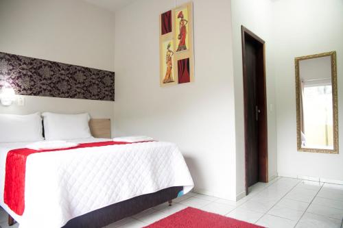 Schlafzimmer mit einem weißen Bett und einem Spiegel in der Unterkunft Hotel Grezelle in Santa Bárbara