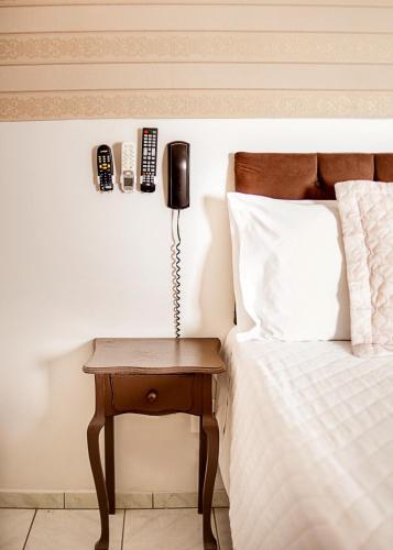 Una cama con teléfono en una mesita de noche junto a una cama en Hotel Grezelle, en Santa Bárbara