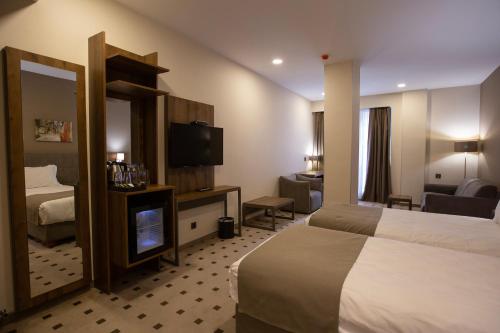 a hotel room with two beds and a television at Avenue Hotel Tbilisi in Tbilisi City