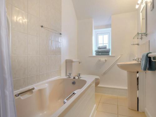 Baño blanco con bañera y lavamanos en Apple Cottage-uk37361 en Lympsham