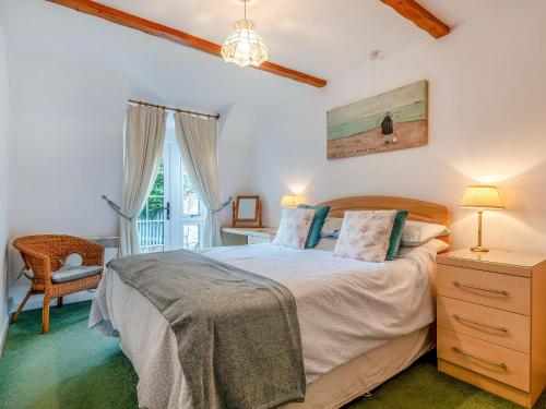 a bedroom with a bed and a chair and a window at Apple Cottage-uk37361 in Lympsham