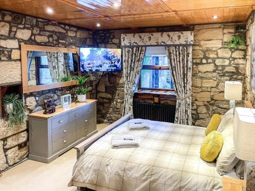 - une chambre avec un grand lit et un mur en pierre dans l'établissement Tennox Stables - Uk39975, à Kilbirnie