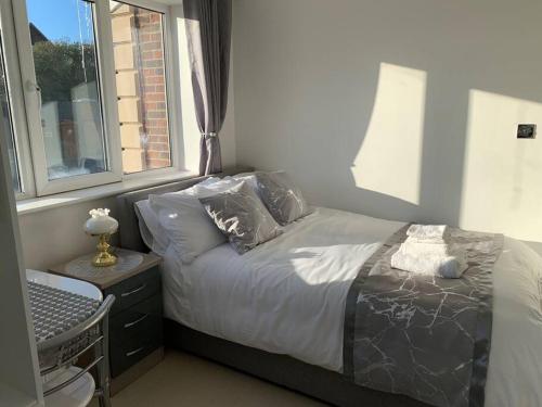 1 dormitorio con cama con almohadas y ventana en Annex B, a Studio flat in London, en Carshalton