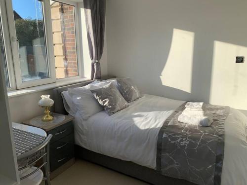 ein Schlafzimmer mit einem Bett mit Kissen und einem Fenster in der Unterkunft Annex B, a Studio flat in London in Carshalton
