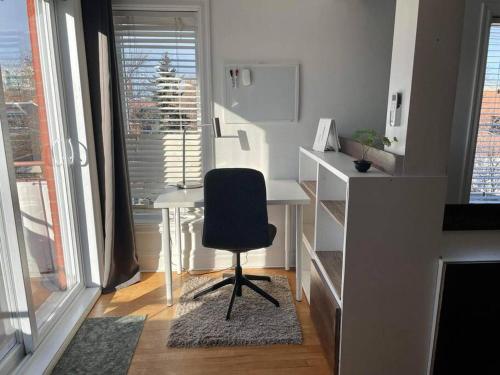 een bureau met een stoel in een kamer met ramen bij Montpetit condo 2 chambres in Montreal