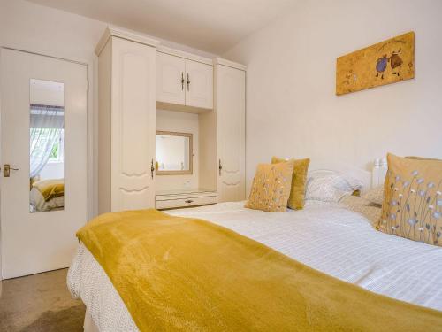 Un dormitorio con una cama con una manta amarilla. en Horseshoe Cottage-uk37360, en Lympsham