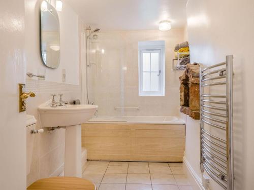 y baño con lavabo, bañera y aseo. en Horseshoe Cottage-uk37360, en Lympsham