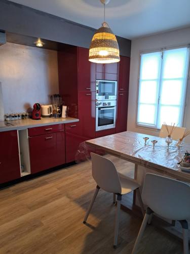 een keuken met rode kasten en een tafel en stoelen bij JeNu in Serris