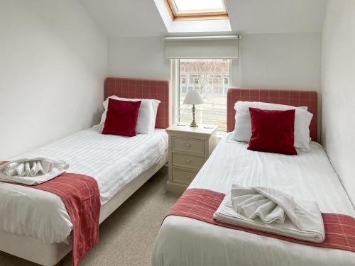 a bedroom with two beds with red pillows and a window at Delaware 7 in Yarmouth