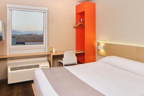 um quarto de hotel com uma cama e uma janela em City Express Junior by Marriott Tijuana Otay em Tijuana