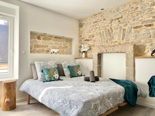 a bedroom with a large bed with a stone wall at LE CALLOCH 2D - Studio 4 Étoiles - Quartier Gare - Wifi - Netflix in Quimper