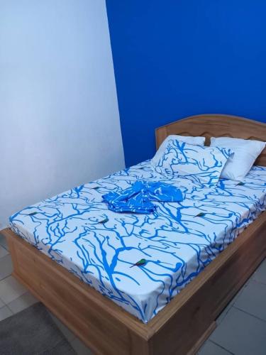 a bed in a room with a blue wall at Studio Mpita in Pointe-Noire