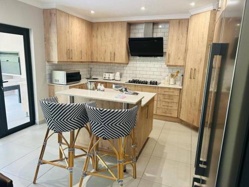 a kitchen with wooden cabinets and bar stools at Angel’s Nest Nelspruit in Nelspruit