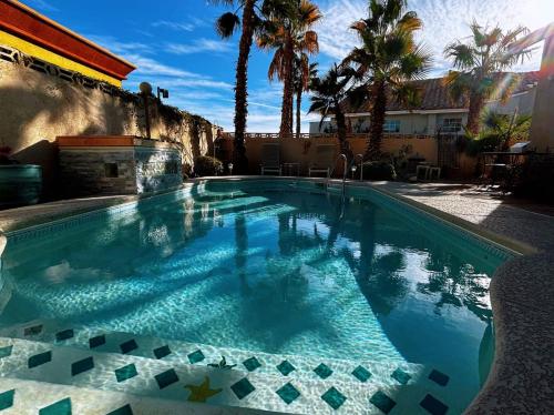 uma piscina com água azul e palmeiras em Fragrant Finnish Sauna & Cozy Pool with French 3br em Las Vegas