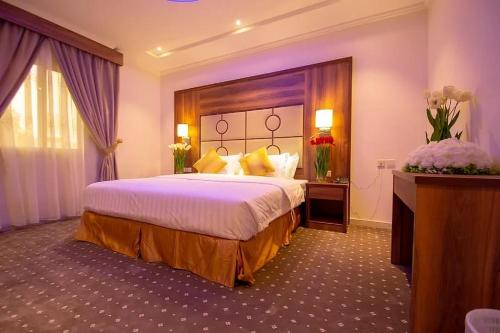 Pokój hotelowy z dużym łóżkiem z żółtymi poduszkami w obiekcie Hayat Al Rose Hotel Appartment w mieście Dżudda