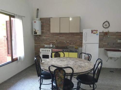 cocina con mesa, sillas y nevera en Dpto Villa Carlos Paz en Villa Carlos Paz