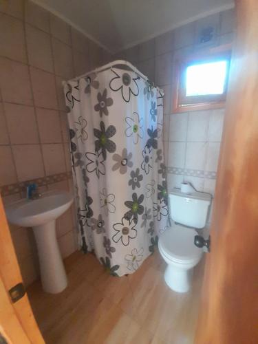 a bathroom with a shower curtain with a toilet and a sink at Cabañas Carampangue in Talagante